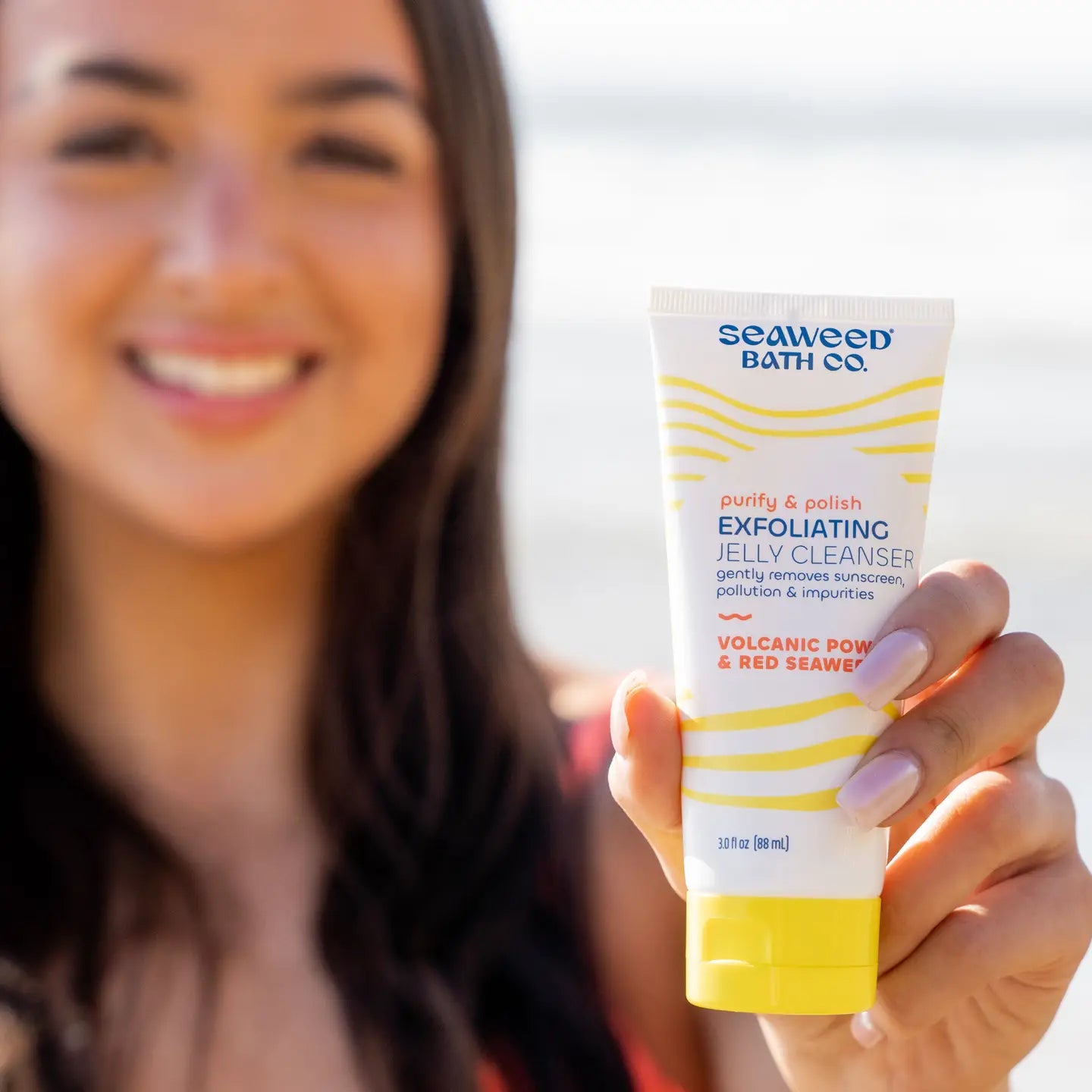 Person holding a Seaweed Bath Co. exfoliating jelly cleanser with a blurred background