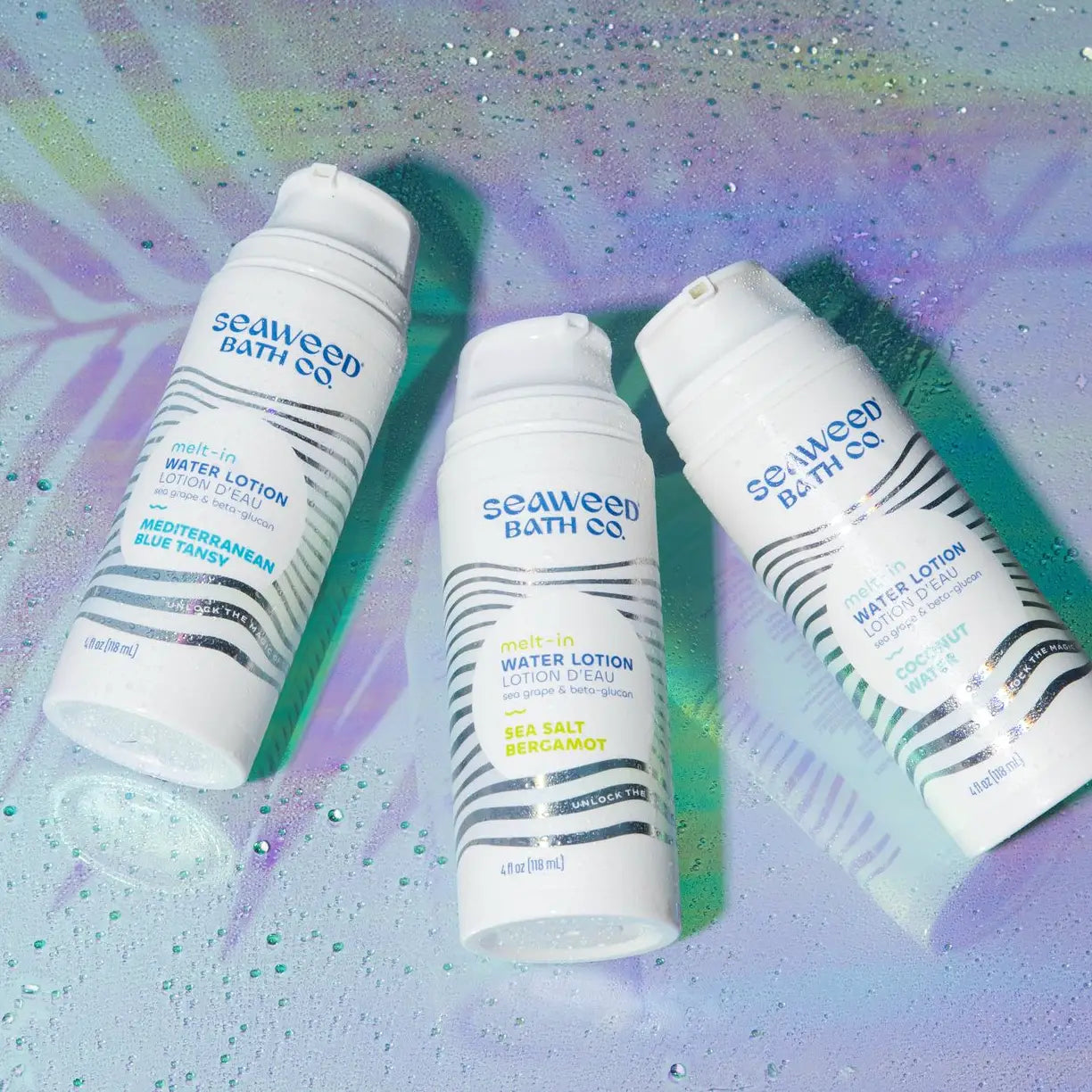 Three bottles of Seaweed Bath Co. water lotion on a colorful, abstract background.