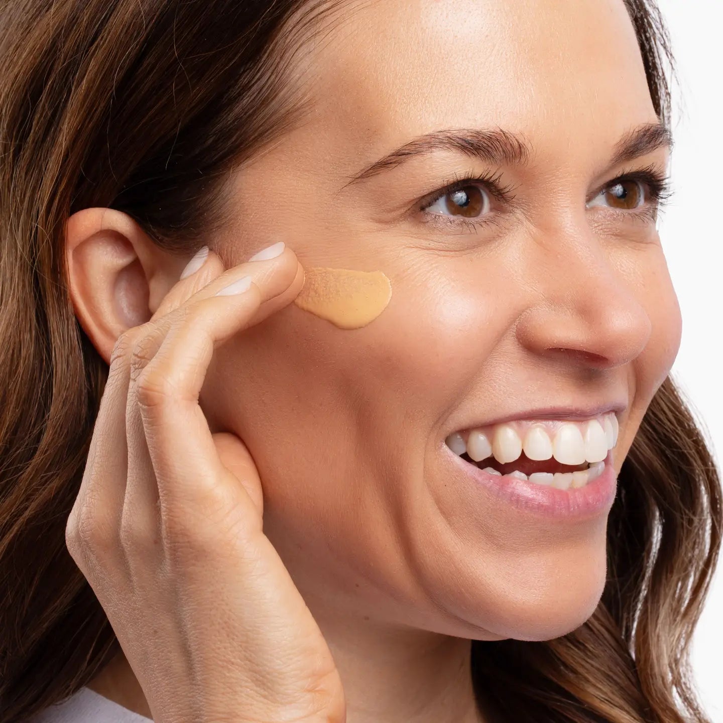 Woman applying Seaweed Bath Co Sheer Tint Face Fluid to her face with a focus on the area around her eye.