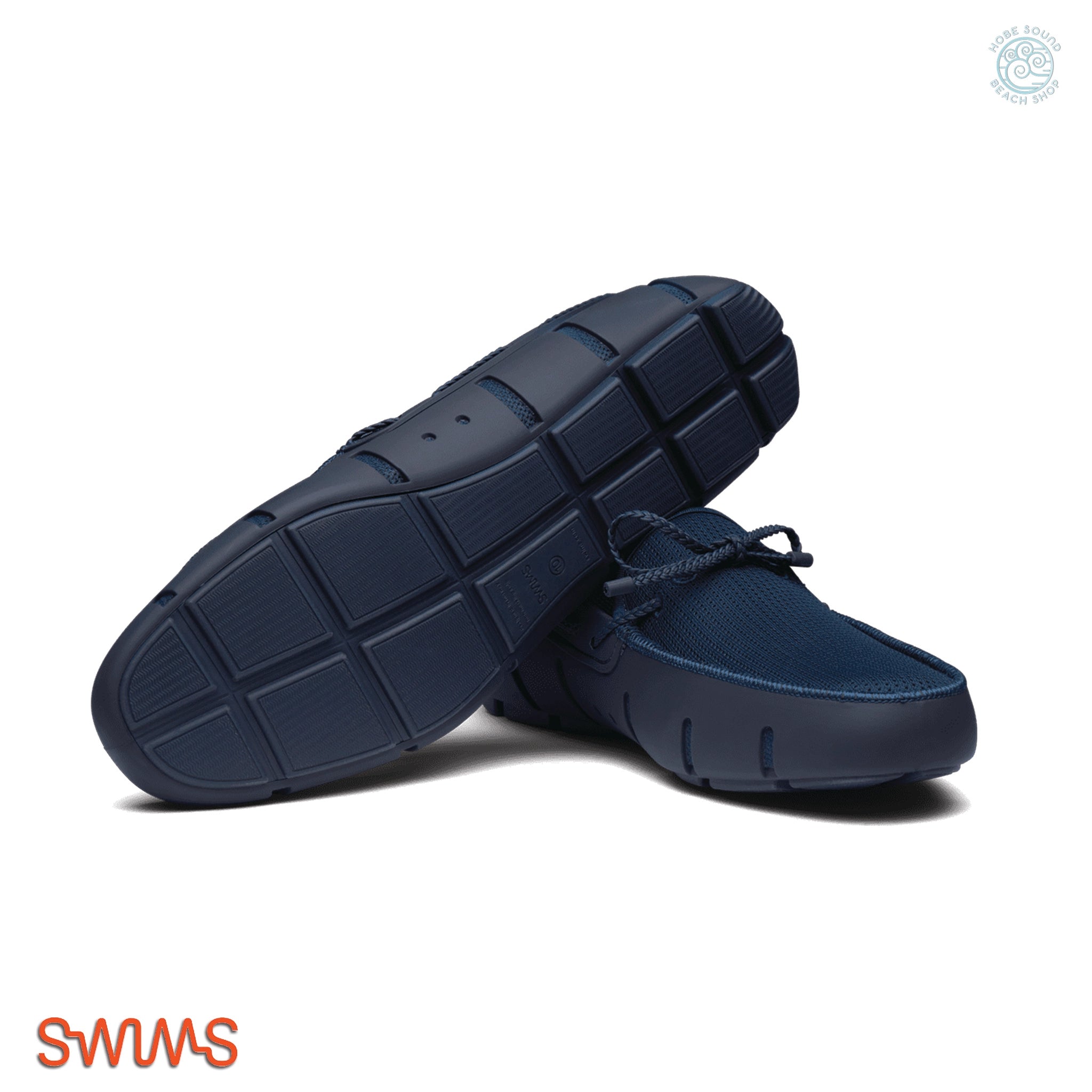 Pair of navy blue shoes with a textured sole on a white background, featuring the Swims brand.