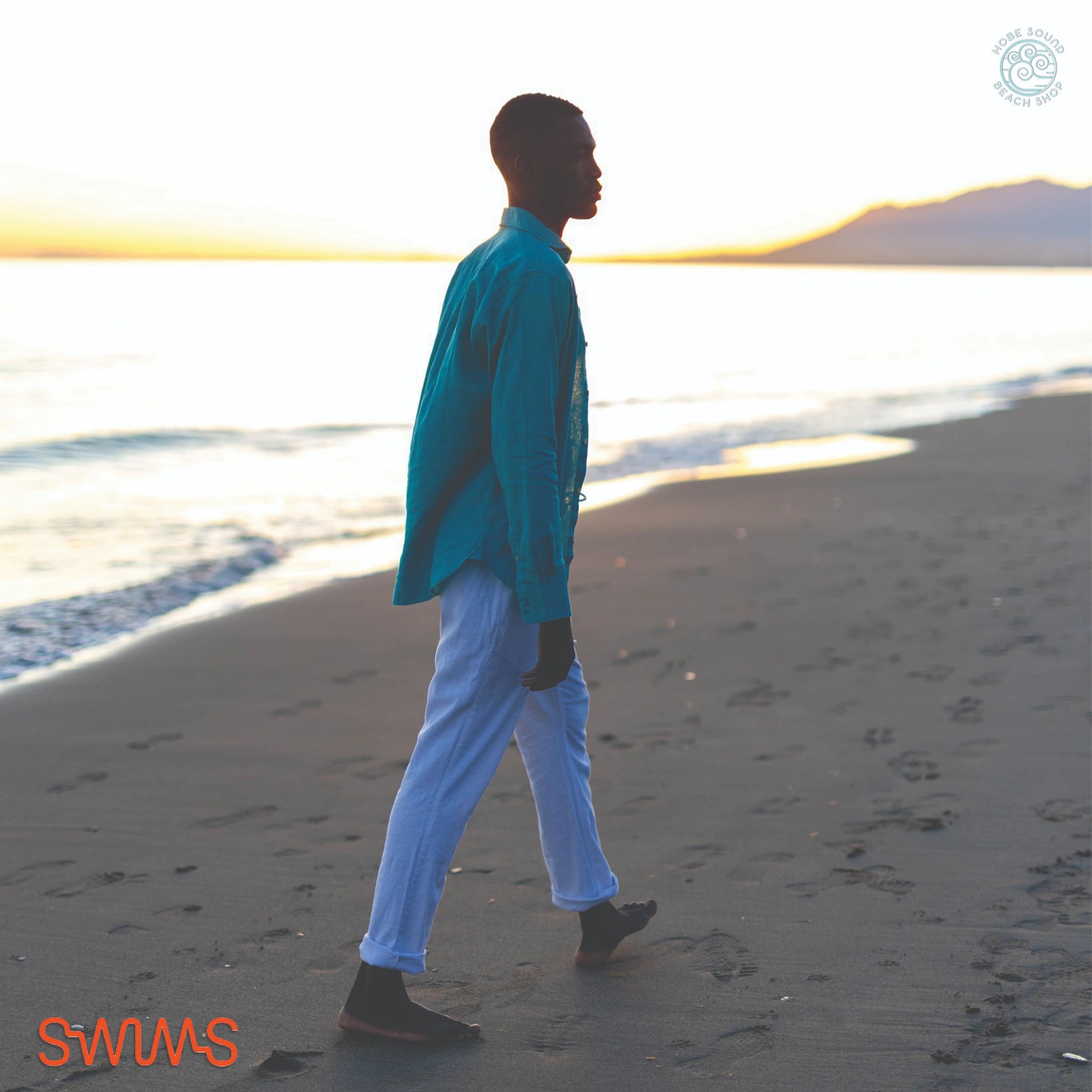 Man walking wearing a Swims Linen Sport Shirt on a beach with a blurred background